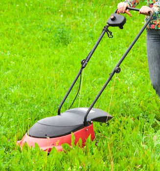 Mowing lawns, lawn mower on green grass