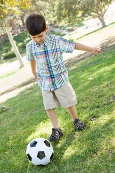 Cute Young Boy Playing with Soccer Ball Outdoors in the Park.