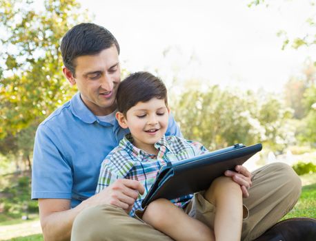 Happy Father and Son Playing on a Computer Tablet Outside.