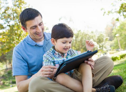 Happy Father and Son Playing on a Computer Tablet Outside.