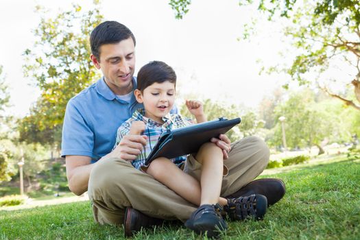 Happy Father and Son Playing on a Computer Tablet Outside.