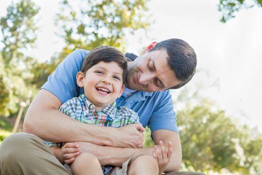 Loving Young Father Tickling Son in the Park.