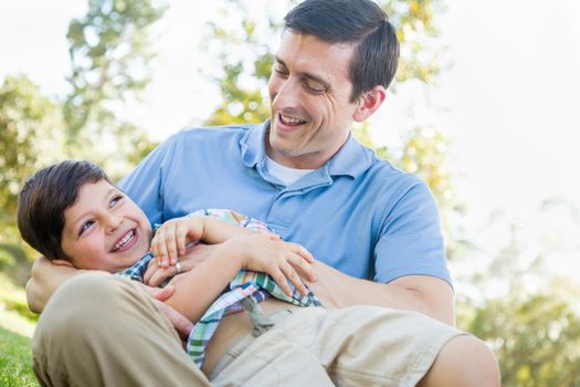 Loving Young Father Tickling Son in the Park.