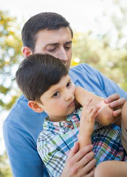 Loving Father Puts a Bandage on the Elbow of His Young Son in the Park.