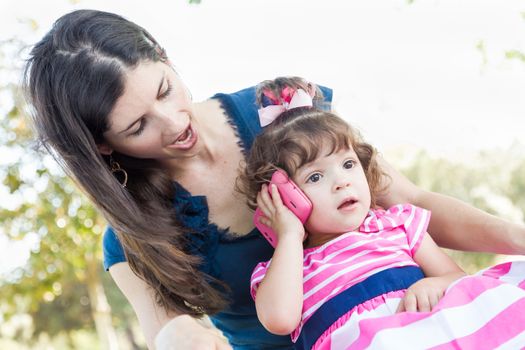 Mixed Race Mother and Cute Baby Daughter Playing with Cell Phone in Park.