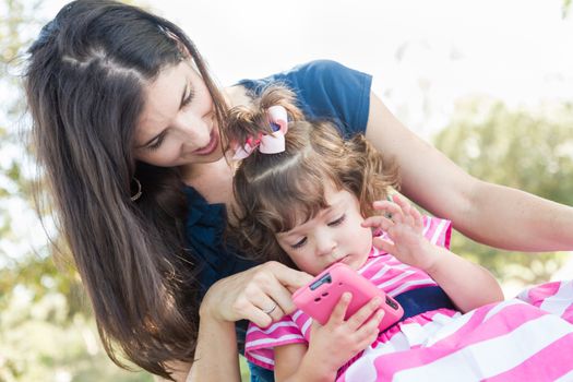 Mixed Race Mother and Cute Baby Daughter Playing with Cell Phone in Park.