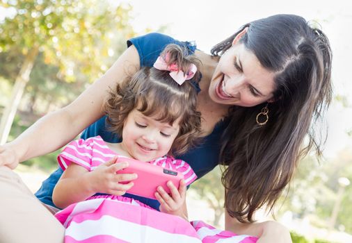 Mixed Race Mother and Cute Baby Daughter Playing with Cell Phone in Park.