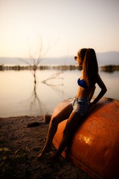 beautiful girl on a rowboat looking at sunset on a lake. half silhouette shot