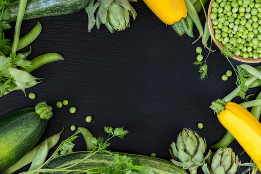 Fresh organic green vegetables on black stone floor with copy space. Green and yellow vegetables background. Healthy eating background. Vegetarian food, organic food.