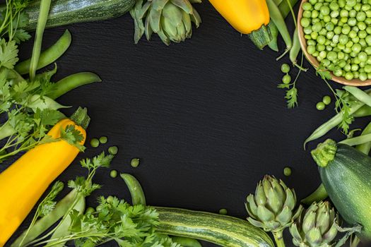 Fresh organic green vegetables on black stone floor with copy space. Green and yellow vegetables background. Healthy eating background. Vegetarian food, organic food.