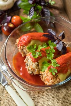 Yummy looking cooked stuffed pepper served in a transparent glass pot on a wooden table