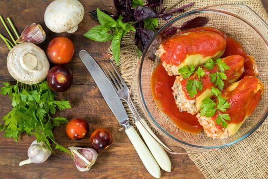 Yummy looking cooked stuffed pepper served in a transparent glass pot on a wooden table. Top view