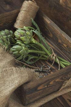 Supplies and materials for artichoke bouquet on wooden background. Top view.