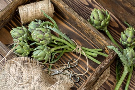 Supplies and materials for artichoke bouquet on wooden background. Top view.