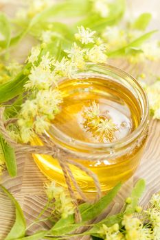 Honey in glass jars with white linden flowers on light wooden background. Shallow depth of field.