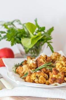 Fried cauliflower in batter on a white plate with white napkin. Close-up