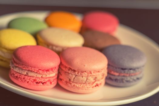Colorful multicolor sweet delicious macaroons on dark background. Shallow depth of field. Coloring toned photo.