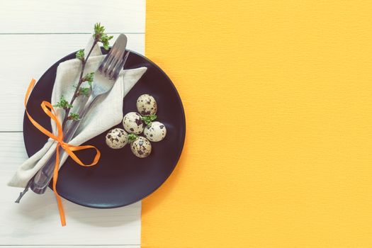 Easter table setting with spring flowers and cutlery. Rustic orange table cloth on white wood background. Holidays background with copy space.