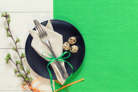 Easter table setting with spring flowers and cutlery. Rustic green table cloth on white wood background. Holidays background with copy space.