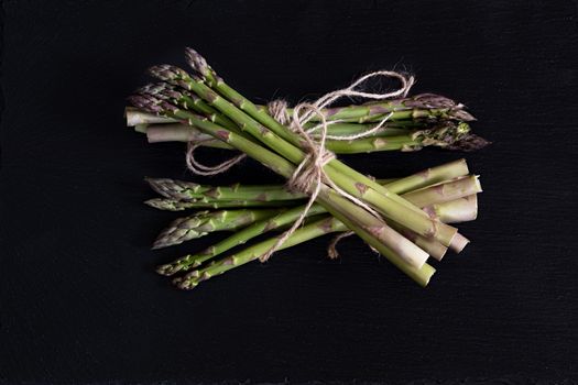 Bunch of fresh green asparagus spears on a black stone background