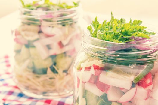 Homemade healthy salads with vegetables, onion, parsley and lettuce in jar. Toning. Selective focus.