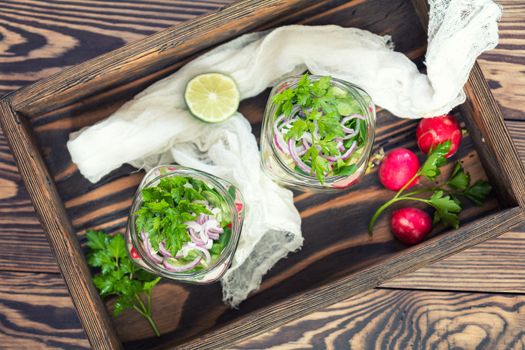 Homemade healthy salads with vegetables, onion, parsley and lettuce in jar. Toning. Selective focus.