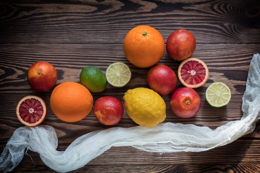 Sicilian Blood oranges, oranges, lemons and limes fruits over old dark wooden background. Top view. Toned.