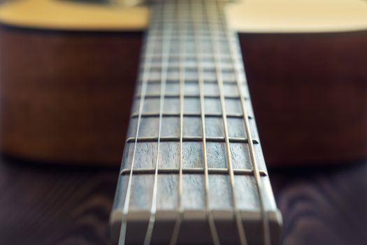 Classic acoustic guitar at weird and unusual perspective closeup. Coloring photo with soft focus. Musical instruments shop or learning school concept