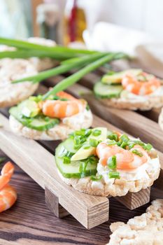 Rice cakes with sliced avocado cucumber shrimp and cream cheese.  Fresh parsley and rosemary. Vegetarian, vegan concept. Shallow depth of field. Coloring and processing photo.