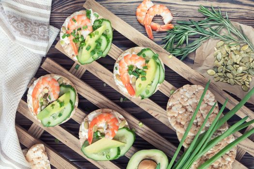 Rice cakes with sliced avocado cucumber shrimp and cream cheese.  Fresh parsley and rosemary. Vegetarian, vegan concept. Shallow depth of field. Coloring and processing photo.