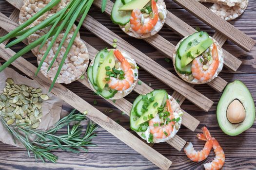 Rice cakes with sliced avocado cucumber shrimp and cream cheese.  Fresh parsley and rosemary. Vegetarian, vegan concept. Shallow depth of field. Coloring and processing photo.