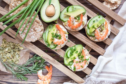 Rice cakes with sliced avocado cucumber shrimp and cream cheese.  Fresh parsley and rosemary. Vegetarian, vegan concept. Shallow depth of field. Coloring and processing photo.