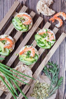 Rice cakes with sliced avocado cucumber shrimp and cream cheese.  Fresh parsley and rosemary. Vegetarian, vegan concept. Shallow depth of field. Coloring and processing photo.