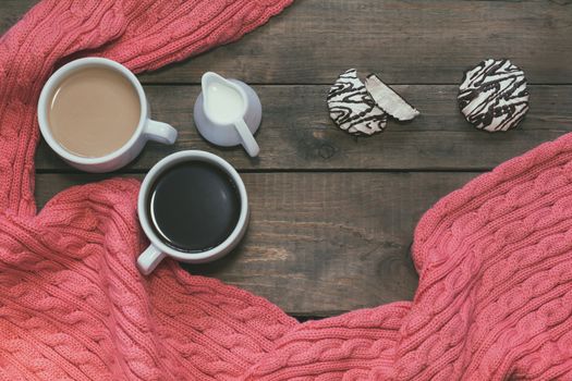 Cup of black coffee, cup of coffee with milk, cream. Pink woven scarf. Marshmallow with chocolate. Dark wooden background. Beautiful vintage coffee groundwork. Coloring and processing photo.