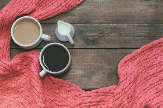 Cup of black coffee, cup of coffee with milk, cream. Pink woven scarf. Dark wooden background. Beautiful vintage coffee groundwork. Coloring and processing photo.