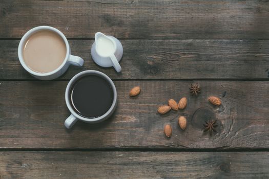 Cup of black coffee, cup of coffee with milk, cream. Almond and anise. Dark wooden background. Beautiful vintage coffee groundwork. Coloring and processing photo.