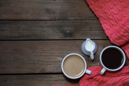 Cup of black coffee, cup of coffee with milk, cream. Pink woven scarf. Dark wooden background. Beautiful vintage coffee groundwork. Coloring and processing photo.