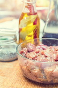 Raw pork neck meat cut in slices with marinated in glass bowl  in a modern kitchen. Shallow depth of field. Toned