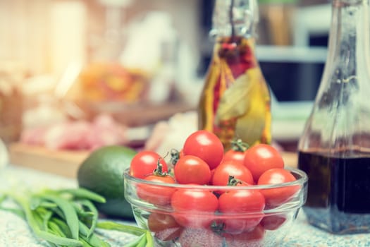 Raw fresh cherry tomatoes in glass bowl in a modern kitchen. Shallow depth of field. Toned