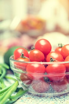 Raw fresh cherry tomatoes in glass bowl in a modern kitchen. Shallow depth of field. Toned