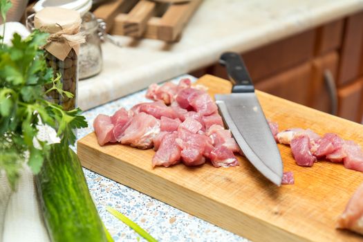 Raw pork neck meat cut in slices on wooden cutting board  in a modern kitchen. Shallow depth of field. Toned