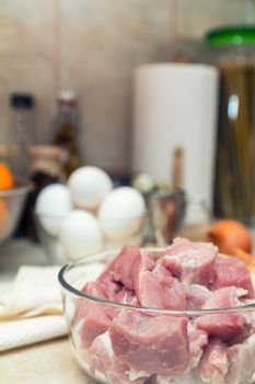 Raw pork neck meat cut in slices on glass bowl. Shallow depth of field. Toned.