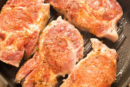 Fresh pork steak with spices cooking on teflon pan grill. Shallow depth of field.