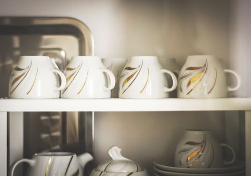 Closeup of white decorated coffee cups in a cupboard