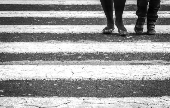 People walking on a zebra crossing. Black and white shot. Urban and cityscape concept