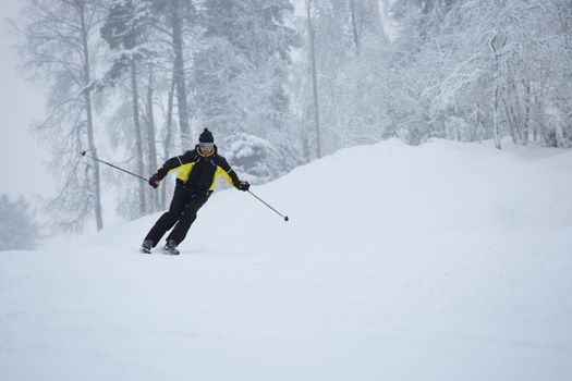 Skier on piste running downhill in beautiful hoarfrost winter landscape