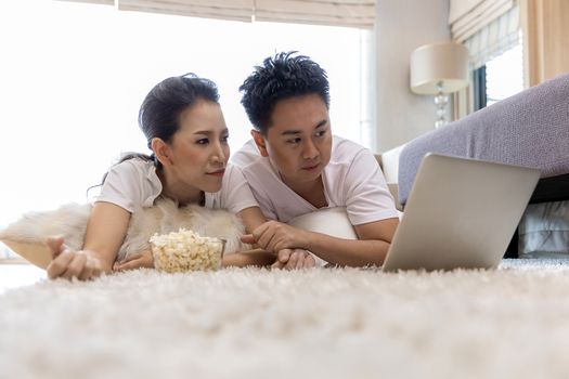 Young Asian Couples using laptop together in bedroom of contemporary house for modern lifestyle concept