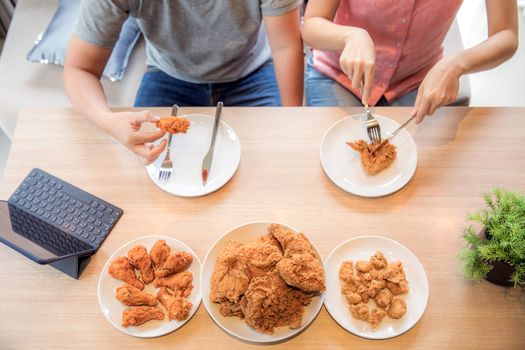 Young Asian Couples eating fried chicken together in living room of contemporary house for modern lifestyle concept Top View