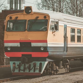 Old yellow passenger diesel train moving at the terminal