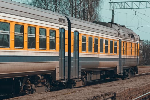 Old yellow passenger diesel train moving at the terminal